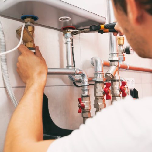 plumber-screwing-nut-pipe-heating-system-boiler-room